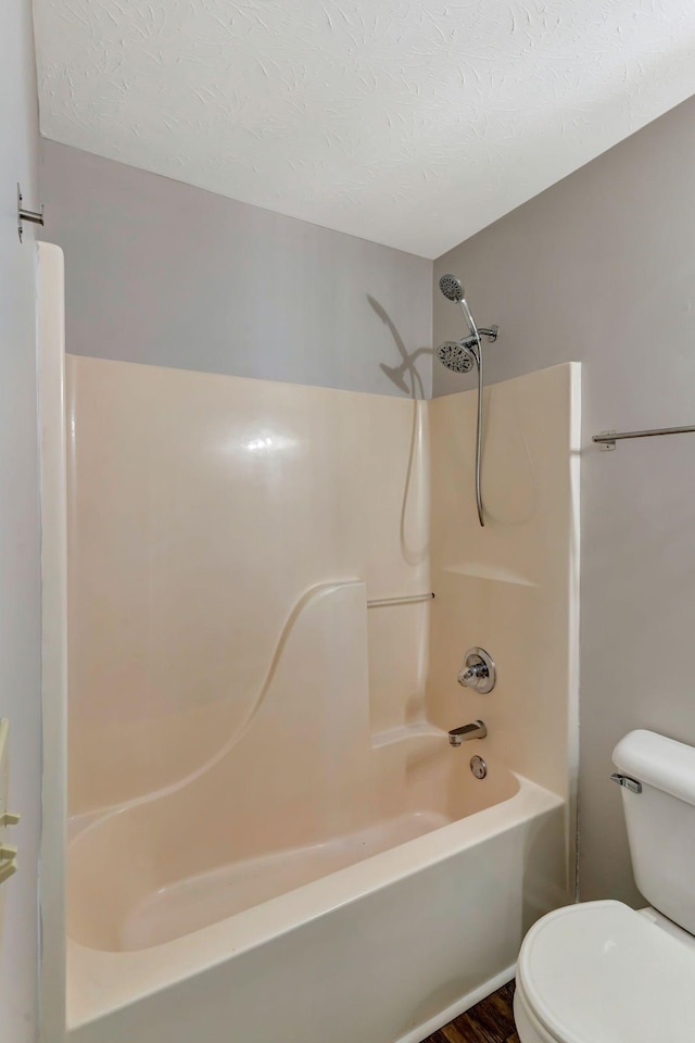 full bathroom featuring wood finished floors, toilet, a textured ceiling, and shower / washtub combination