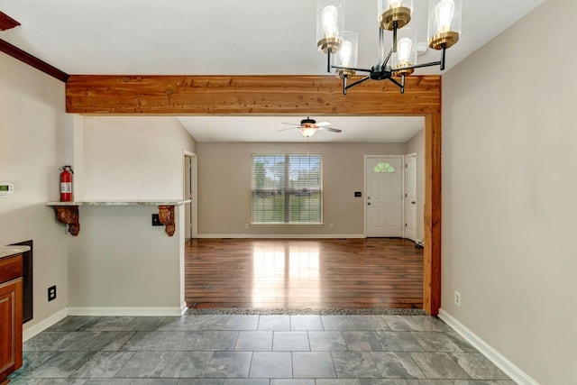 interior space featuring baseboards and ceiling fan with notable chandelier