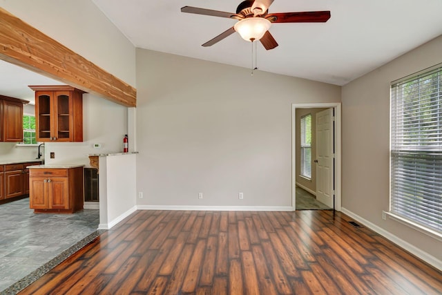 unfurnished living room featuring dark wood-type flooring, a ceiling fan, vaulted ceiling, and a wealth of natural light