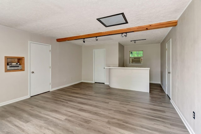 unfurnished living room featuring baseboards, a textured ceiling, wood finished floors, and cooling unit