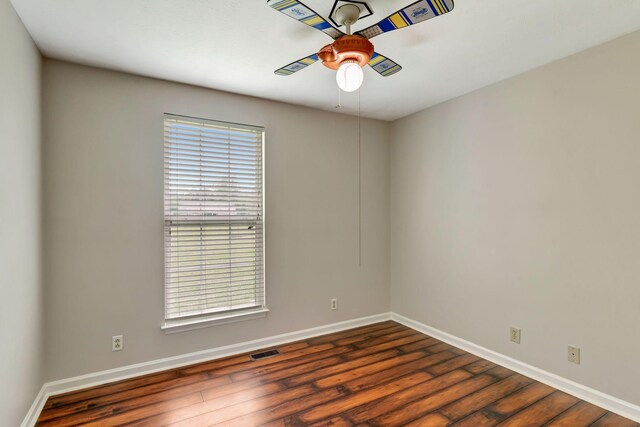 spare room with baseboards, ceiling fan, dark wood-style floors, and visible vents