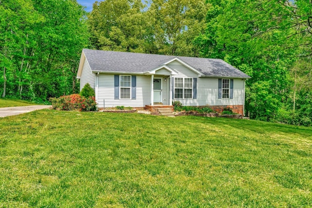 ranch-style home featuring roof with shingles and a front yard