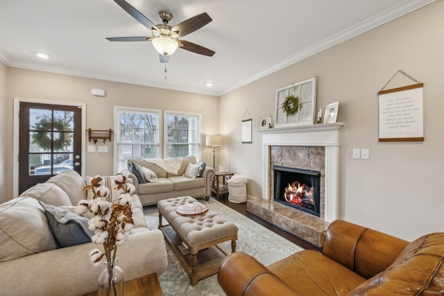 living area featuring a healthy amount of sunlight, ornamental molding, a fireplace, and a ceiling fan