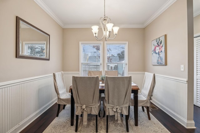 dining area featuring an inviting chandelier, crown molding, wainscoting, and wood finished floors