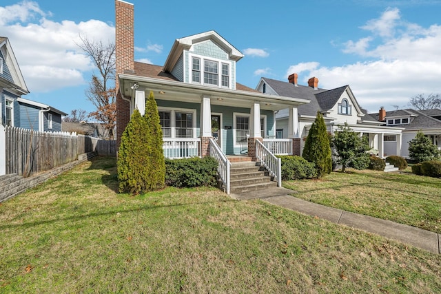 bungalow-style home with fence, covered porch, a chimney, and a front yard