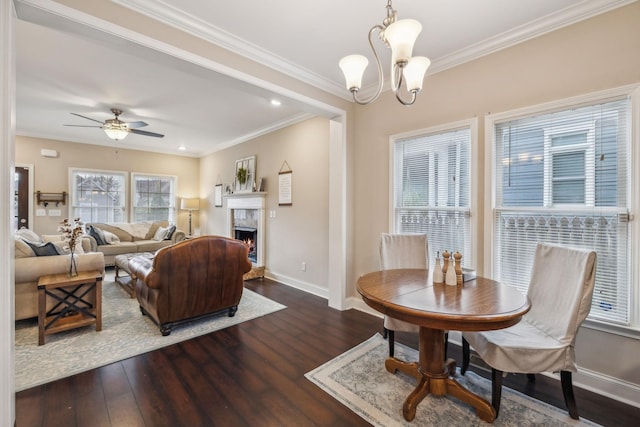 dining area with crown molding, baseboards, wood finished floors, and a fireplace