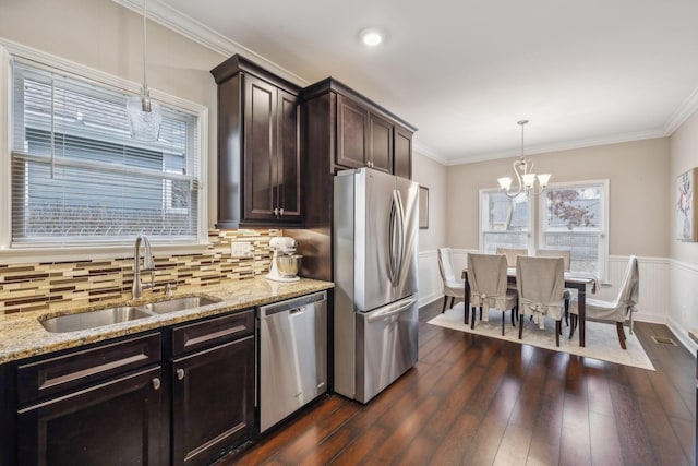 kitchen with light stone countertops, dark wood finished floors, a sink, a chandelier, and stainless steel appliances
