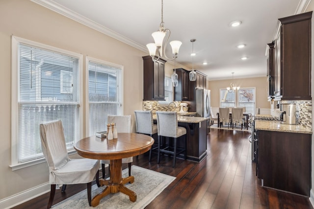 dining space featuring crown molding, dark wood finished floors, and a notable chandelier