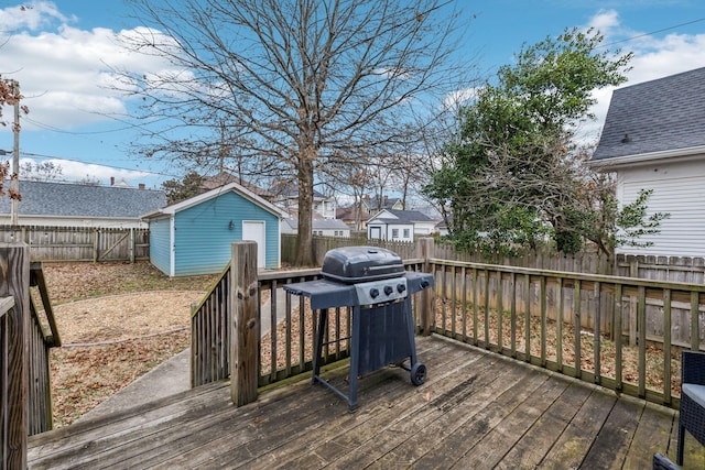 wooden terrace featuring a fenced backyard, an outdoor structure, grilling area, and a residential view