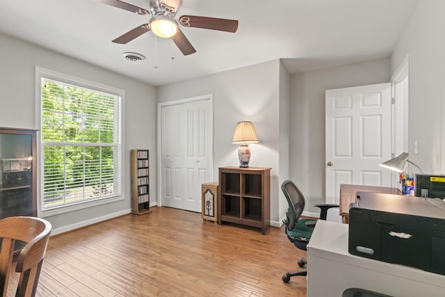 home office with baseboards, ceiling fan, light wood finished floors, and visible vents