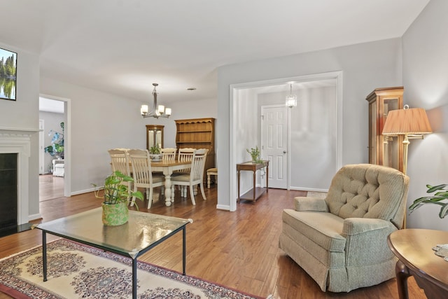 living area with baseboards, wood finished floors, and a chandelier
