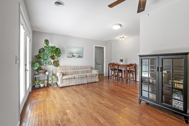 living area featuring visible vents, a ceiling fan, plenty of natural light, and wood finished floors