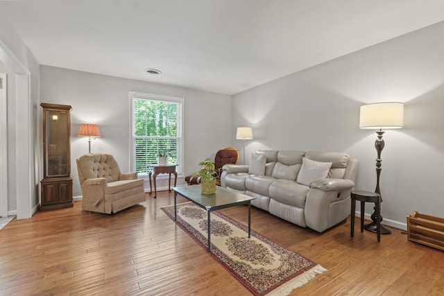 living room featuring baseboards, light wood-style flooring, and visible vents