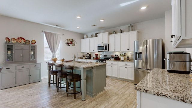 204 Princeton Dr, Lebanon, TN 37087 - kitchen featuring stainless steel appliances, light wood finished floors, backsplash, a kitchen breakfast bar, and white cabinets