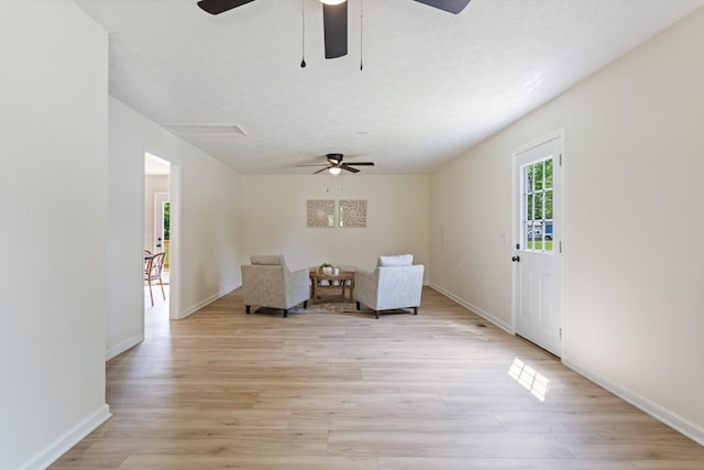 sitting room featuring baseboards, a ceiling fan, and light wood-style flooring
