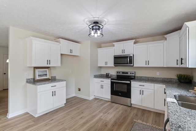 kitchen featuring light wood-style floors, baseboards, stainless steel microwave, and electric stove