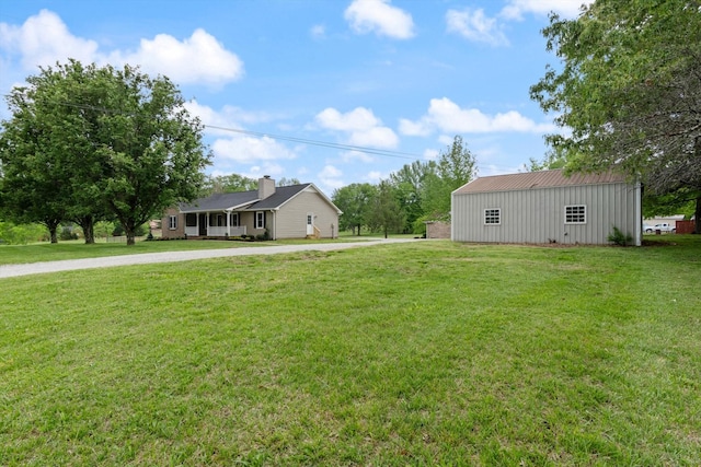 view of yard featuring concrete driveway, a pole building, and an outdoor structure