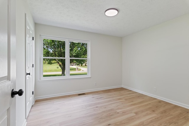 spare room featuring baseboards, visible vents, and light wood-type flooring