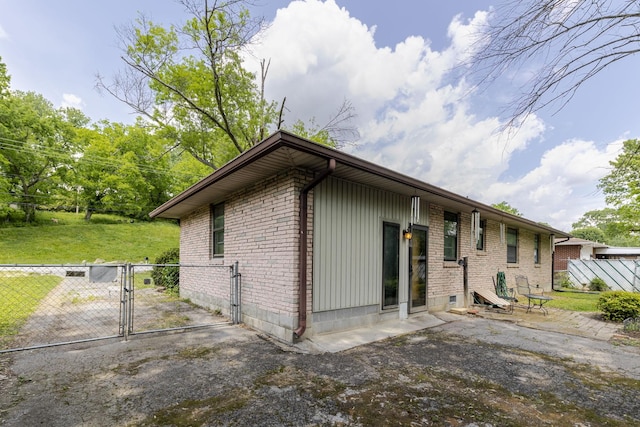 view of side of home with a patio, brick siding, fence, and a gate
