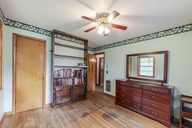 bedroom featuring heating unit, baseboards, ceiling fan, and light wood-type flooring