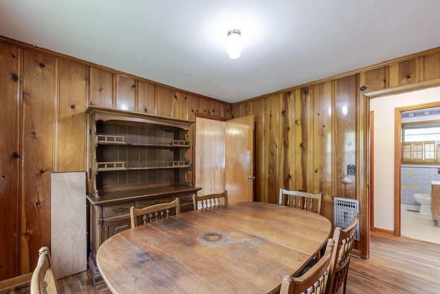 dining space with wood walls, heating unit, and wood finished floors