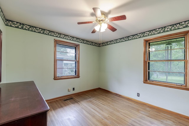 spare room with light wood-style floors, baseboards, plenty of natural light, and visible vents