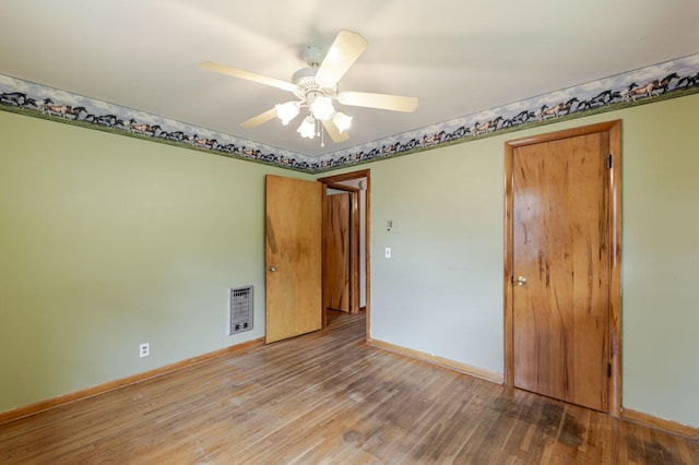 spare room with baseboards, ceiling fan, wood finished floors, and visible vents