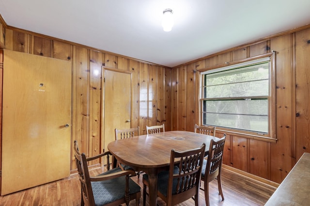 dining room featuring crown molding, light wood-style flooring, and wooden walls