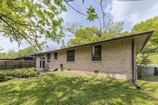 rear view of property featuring a lawn, fence, and brick siding