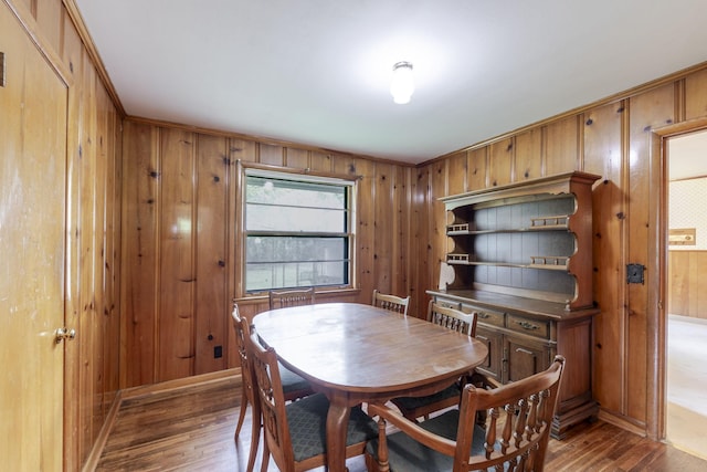 dining room with wooden walls and wood finished floors