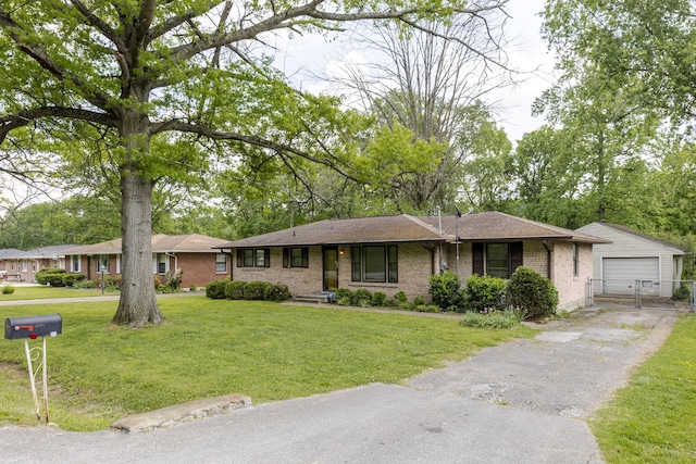 ranch-style house featuring an outdoor structure, brick siding, aphalt driveway, and a front yard