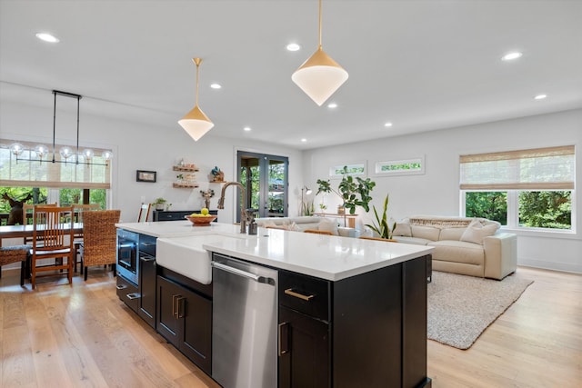 kitchen featuring a sink, light countertops, stainless steel dishwasher, and light wood-type flooring