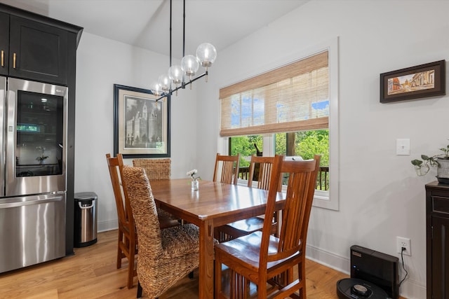 dining room with baseboards, light wood-type flooring, and a notable chandelier
