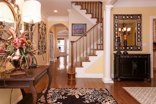 entryway featuring crown molding, arched walkways, dark wood finished floors, baseboards, and stairway