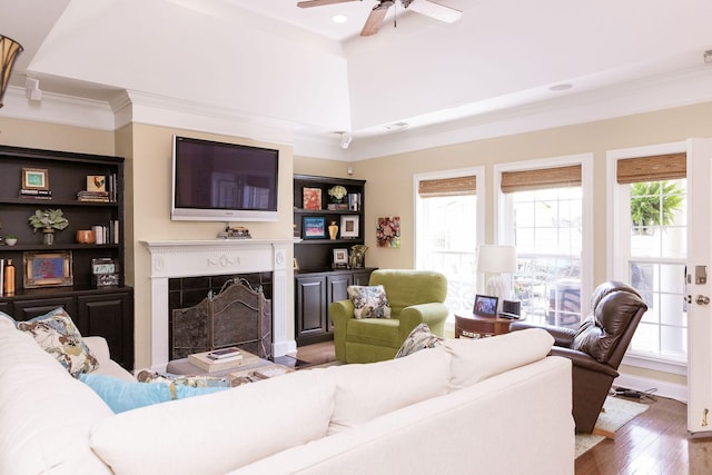 living area with ceiling fan, ornamental molding, wood finished floors, and a fireplace