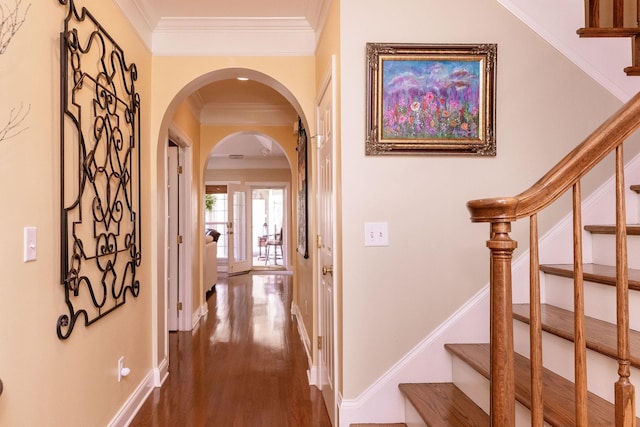 corridor with crown molding, arched walkways, dark wood-type flooring, and stairway