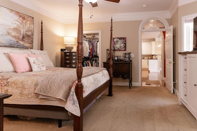 bedroom featuring a walk in closet, light colored carpet, crown molding, a closet, and connected bathroom