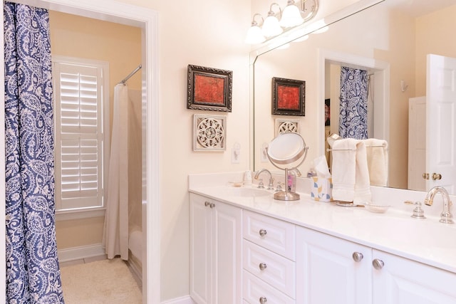 bathroom with a sink, baseboards, and double vanity