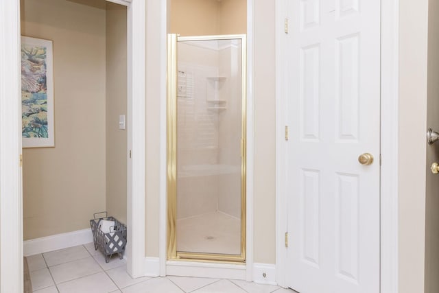 full bath featuring tile patterned flooring, baseboards, and a shower stall