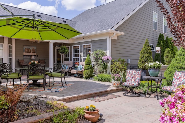 back of house with outdoor dining area, roof with shingles, and a patio area