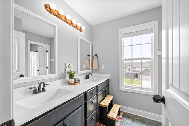 bathroom featuring baseboards, a wealth of natural light, and a sink