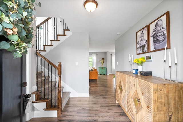 entryway featuring baseboards, wood finished floors, and stairway