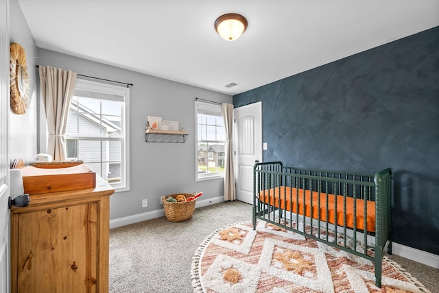carpeted bedroom with baseboards and a nursery area
