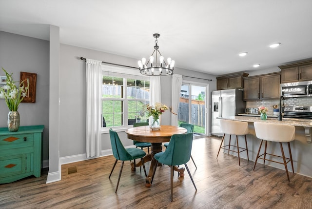 dining area with dark wood-style flooring, an inviting chandelier, recessed lighting, baseboards, and visible vents