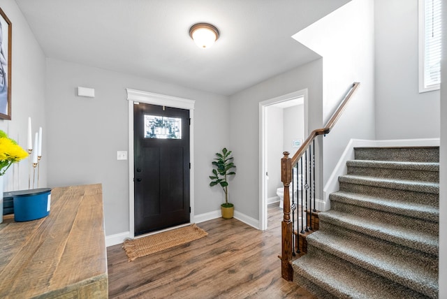 foyer entrance with baseboards, stairs, and wood finished floors