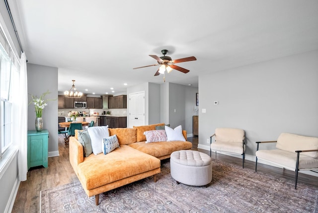 living area featuring light wood-style floors, recessed lighting, baseboards, and ceiling fan with notable chandelier