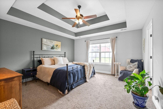 bedroom with ceiling fan, visible vents, a raised ceiling, baseboards, and carpet