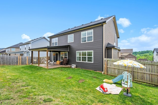 rear view of house with a lawn, a fenced backyard, and a patio area