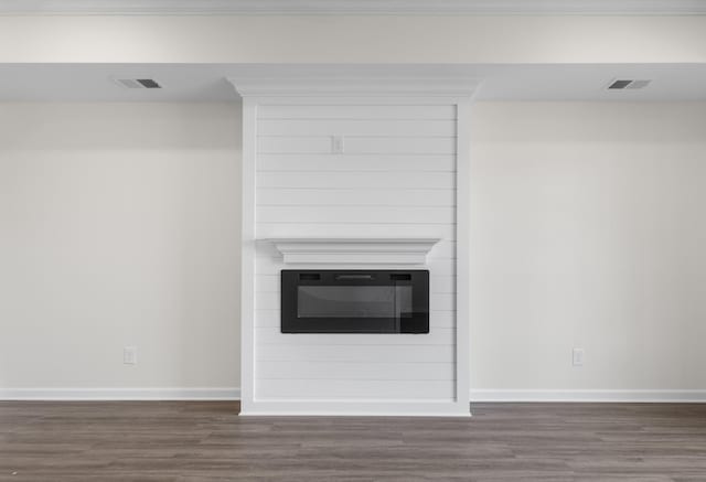 room details with baseboards, a large fireplace, wood finished floors, and visible vents