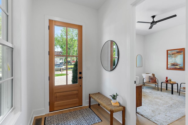 entrance foyer with a ceiling fan, baseboards, visible vents, and wood finished floors